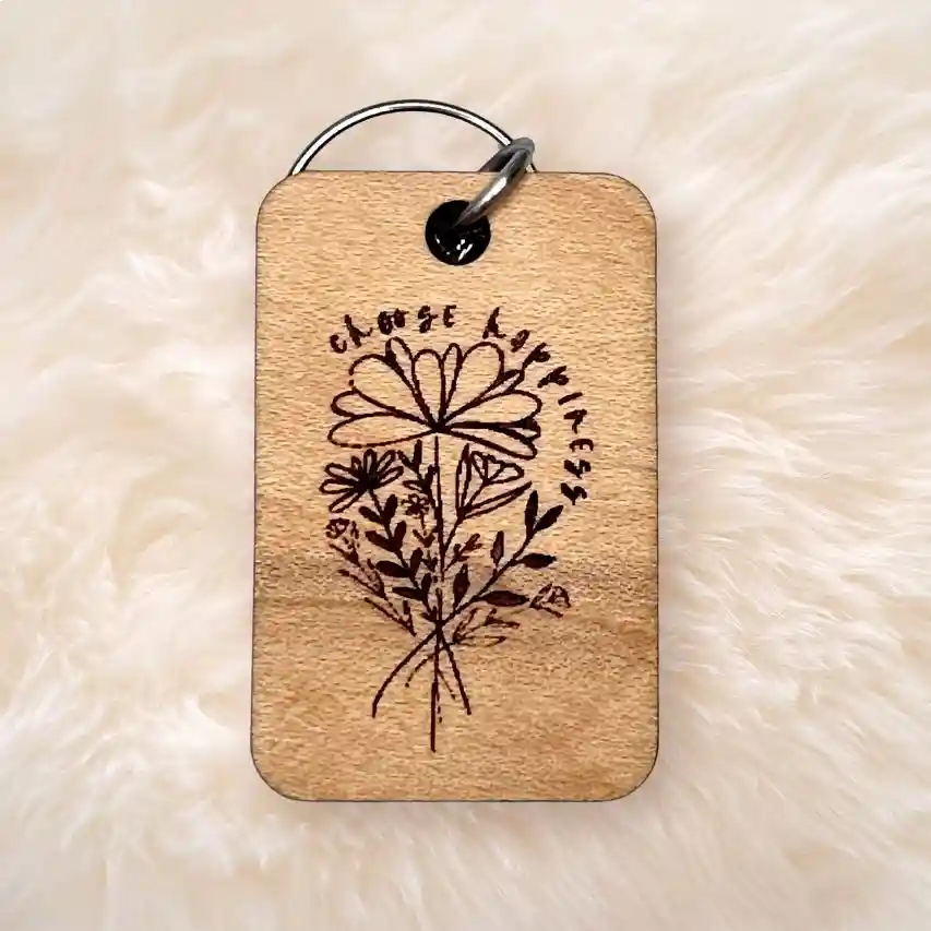 Wooden keychain with engraved floral design and  choose happiness on a soft beige background