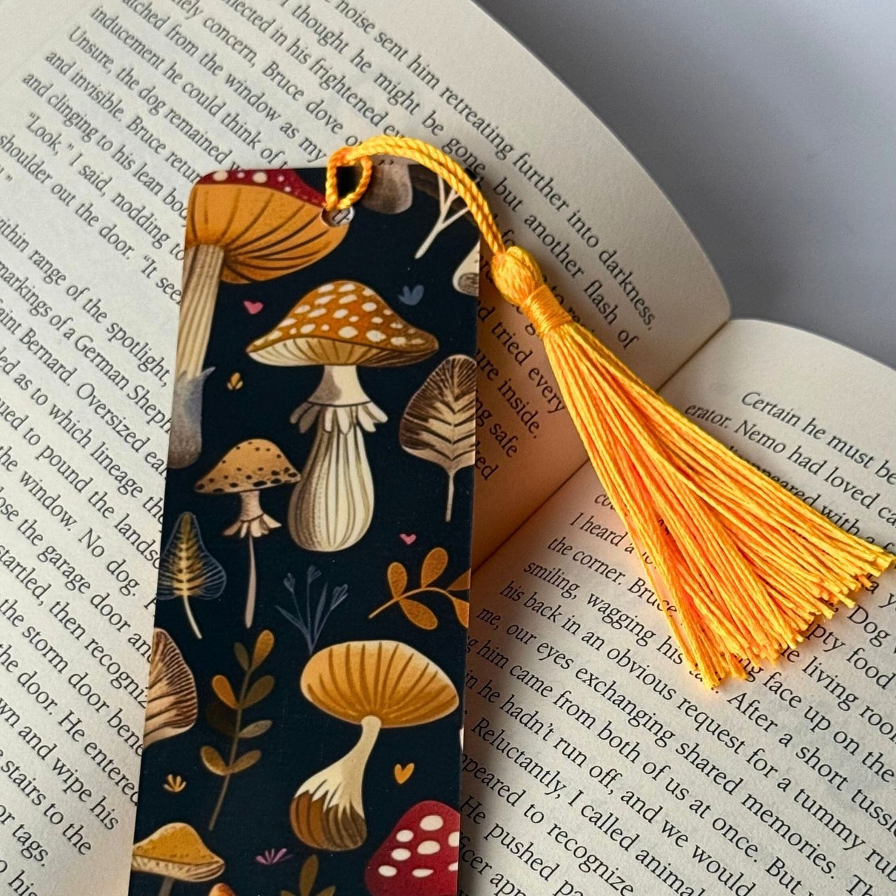 Black mushroom botanical bookmark with yellow tassel on an open book.