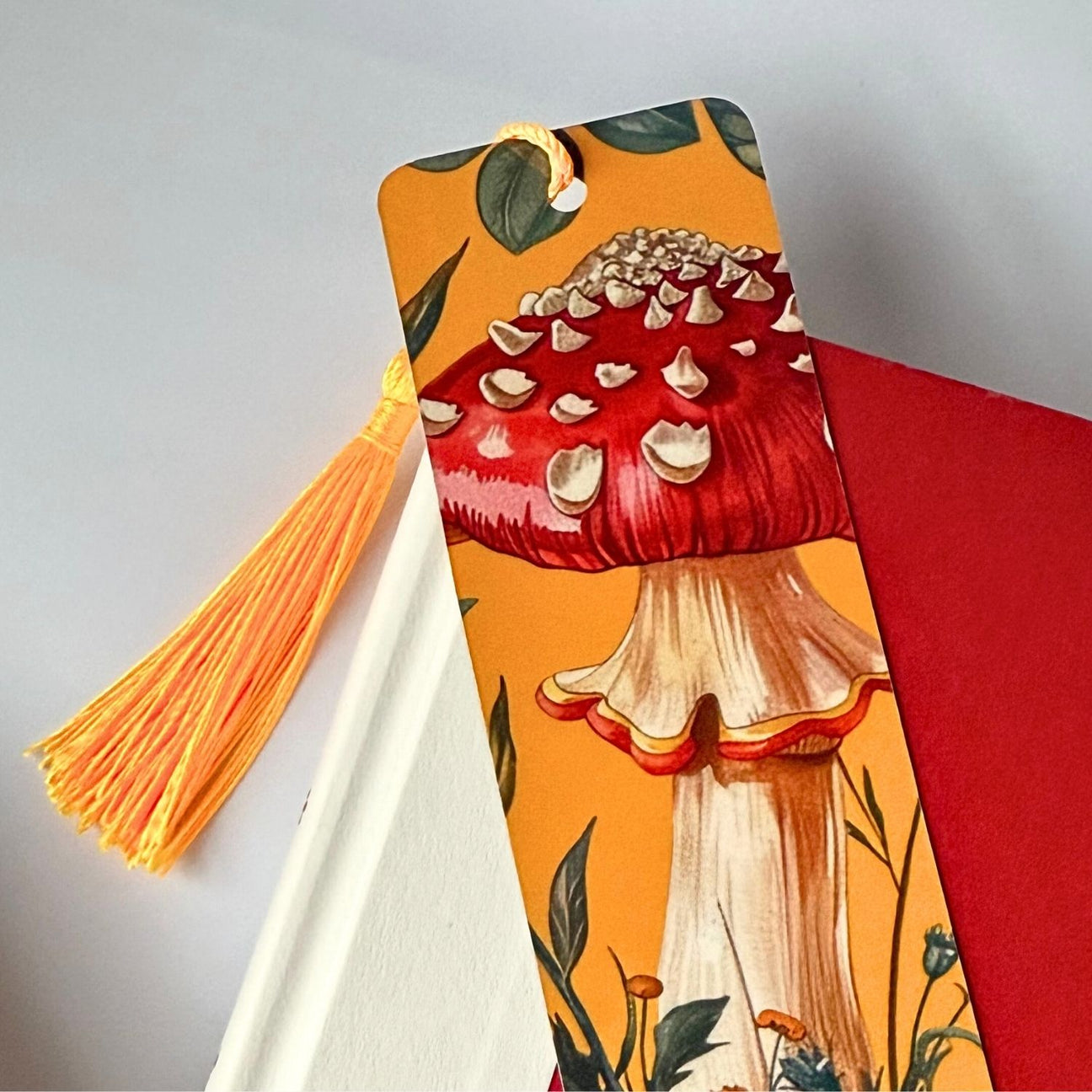 Yellow bookmark on top of a red book against a light grey background.