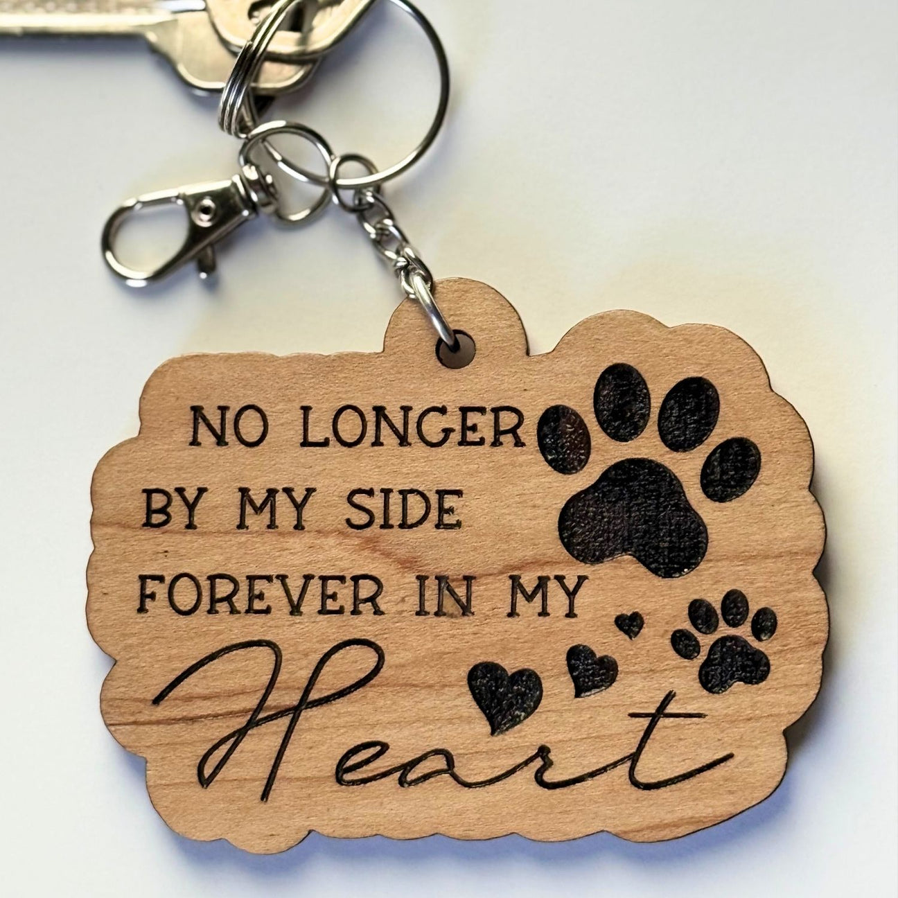 Wooden keychain with paw prints and text on a white background