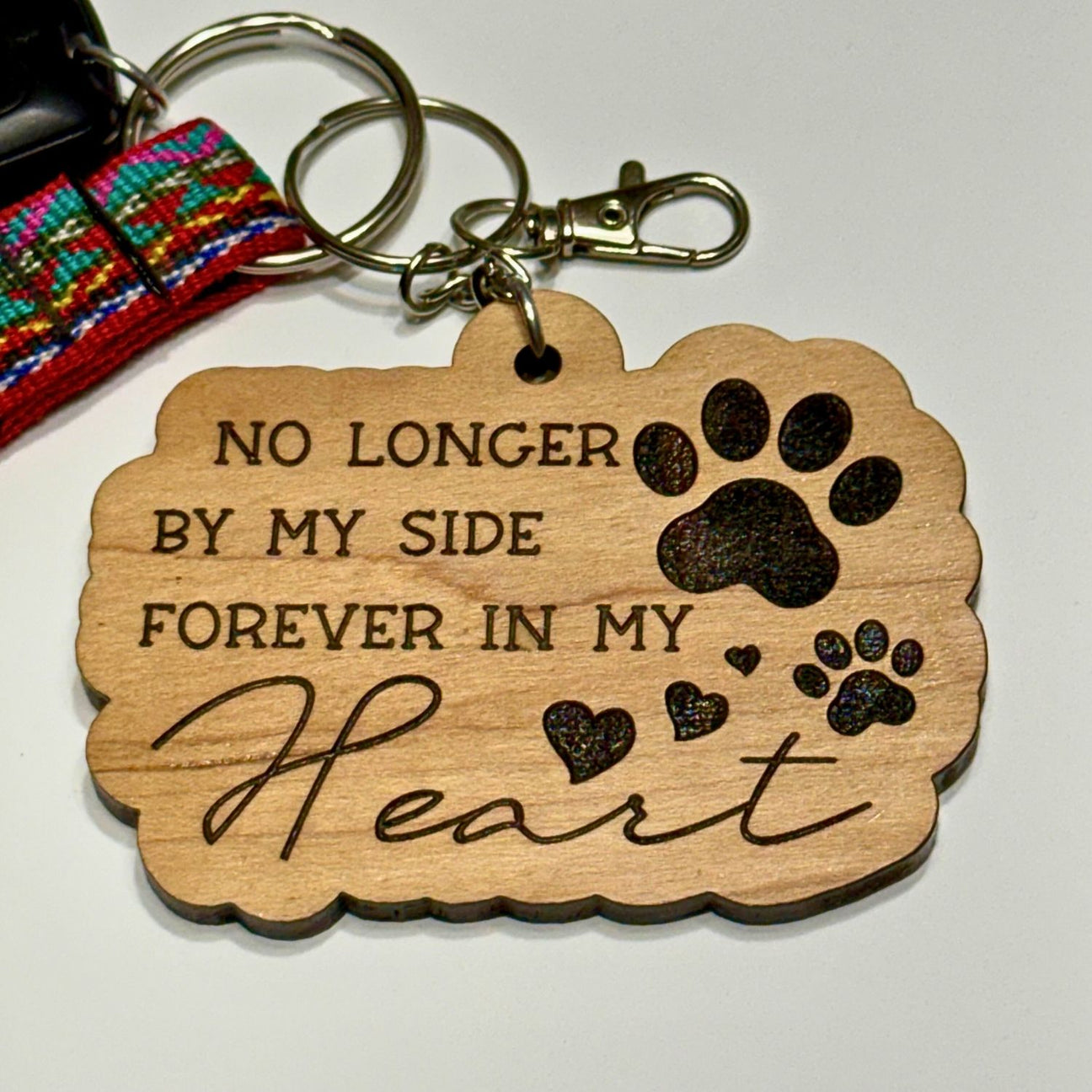 Wooden keychain with engraved text and paw prints on a white background