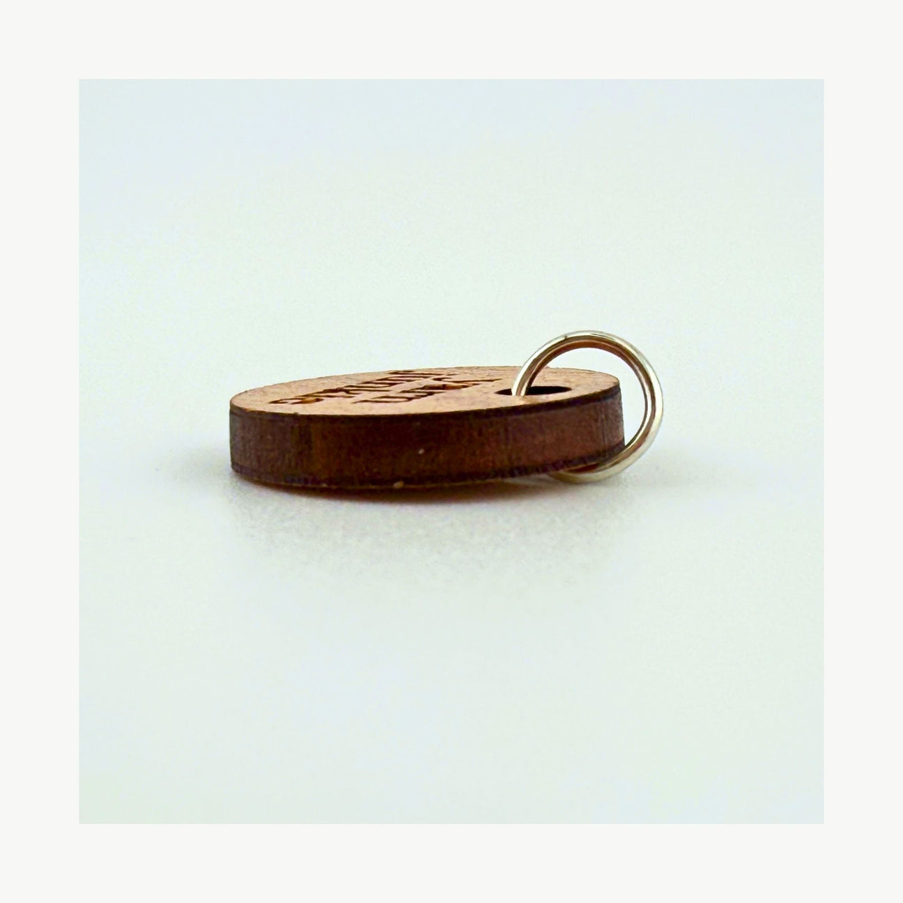 Wooden stitch marker with a metal ring on a light blue background