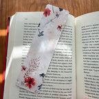 Tan floral bookmark laying on a book on a brown table.