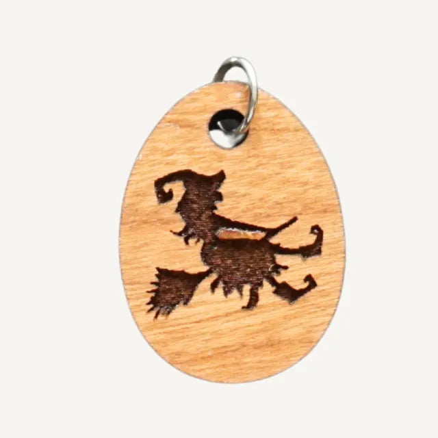 charm with witch riding a broomstick on a white background