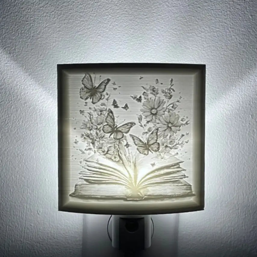 lithophane nightlight with an open book with butterflies and flowers on a white wall