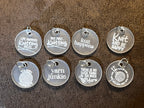 A set of nine clear acrylic stitch markers with engraved knitting-related phrases, displayed on a textured background.