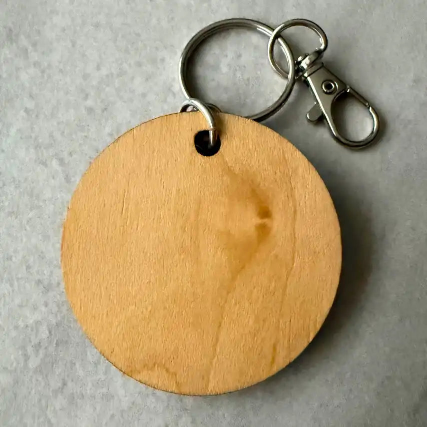 Wooden keychain with metal clip on a gray background