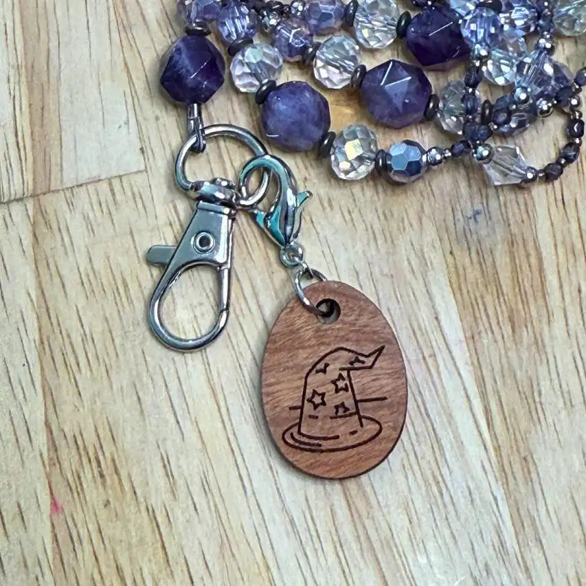 Lanyard with purple beads and a wooden charm on a wooden surface