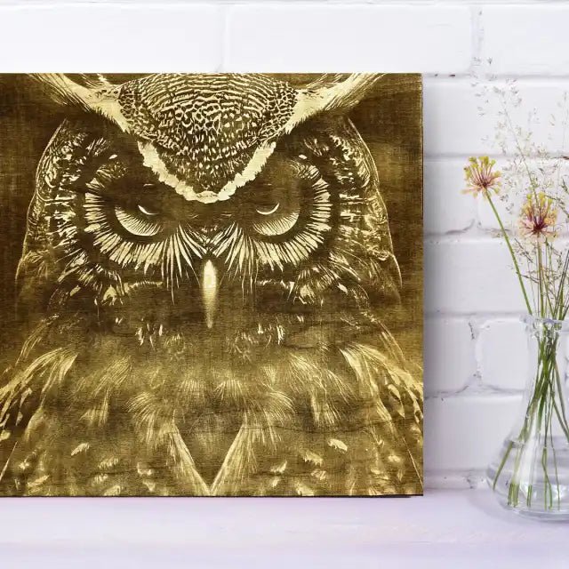 Owl engraving on a white brick wall with a vase of flowers.