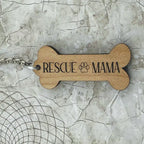 Wooden bone-shaped keychain with 'Rescue Mama' text on a textured surface